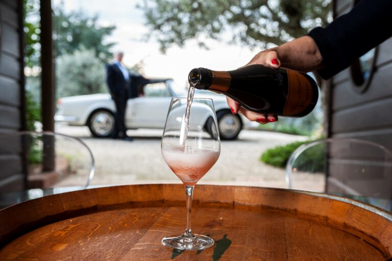 Bicchiere di vino Montechiari che viene riempito su una botte nella campagna toscana